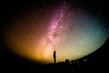 a silhouette of a person looking up at a bright starry sky