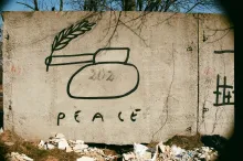 Hand-drawn tank on cement wall with peace written underneath.
