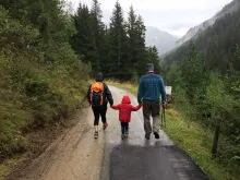 A family of three walking on a road in the mountains