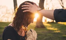 A minister laying hands on a women's head and praying after water baptism.