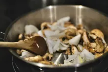 Vegetable and mushrooms being sauted in a pan.