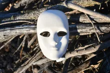 White mask on top of a pile of sticks