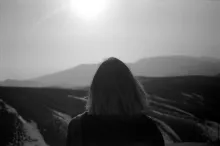 A woman looking at over a vista - a challenge to travel through.