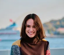 a smiling woman with a body of water in the background