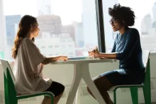 Two young women talking at a small table.