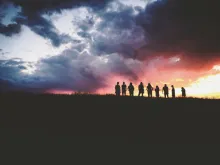 Silhouette of nine persons standing on the hill.