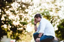 a man sits outside with his head in his hand