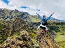 Woman sitting on rocky mountain during daytime.