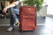 a woman sitting beside a suitcase and holding a passport