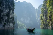 a body of water with a boats surrounded by green cliffs