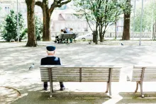 an elderly man sitting on a bench in a park