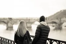 a man and a woman in a grayscale of a bridge of a body of water