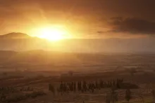 A sunrise coming over a mountain top lighting up the valley below.
