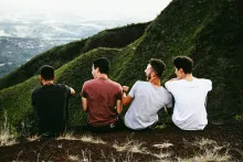 Four young men sitting outdoors in the mountains