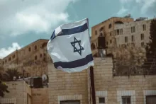 an israel flag flying in front of stone buildings in Jerusalem