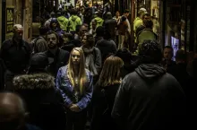 A woman walking in a crowded alley with numerous people.