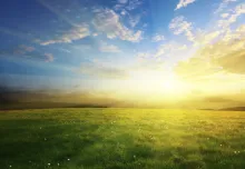 Sunrise of over a green grass hill