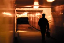 A man walking down a tunnel hallway.