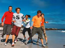 Young adults running on the beach.