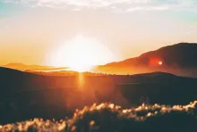 Sun rays shining over hills.
