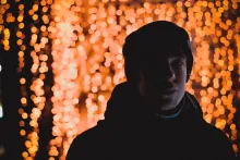 A young man standing in front of red lights.