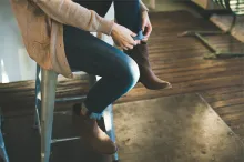 A woman sitting on a bench adjusting her shoes.