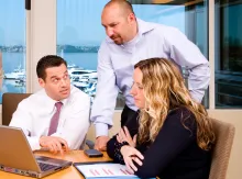 A group of people working together at a table using laptops.
