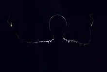 A shadow silhouette of a man with arms in the air.