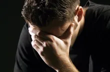 Um jovem segurando a cabeça com as mãos em tristeza ou remorso.