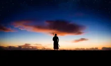 Photo illustration of a shepherd standing in field at dark.