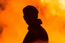 A silhouette of a man with smoke and flames around him.