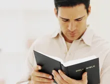 A man holding and reading a Bible.