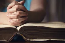 A person with their hands on top of a Bible.