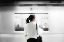 Uma mulher em pé vendo um trem passando.