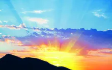 Sun rays shining over hills.