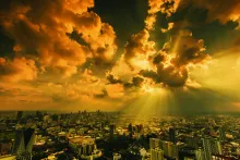Sun rays shining through clouds on a city.