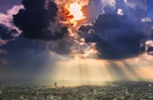 Sun rays and clouds over a big city.