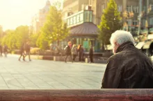 An old man sitting on a park bench looking down.