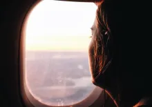 A young women looking out the window of an airplane.