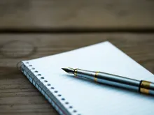 A writing pen on top of spiral bound notebook.