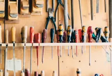 A workbench wall with many types of screwdrivers hanging.