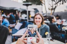 A woman taking a photo of another women with a smartphone.