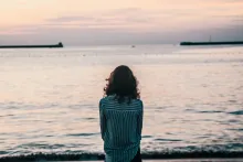 A woman sitting by a large body of water.