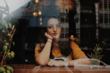 A young woman sitting with her arms on a counter looking through a window.