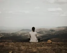 A woman sitting beside herself looking at the view of mountains.