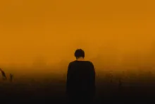 A person with their head down. The sky is red.