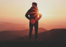 A person standing on the rock with the sun behind them.