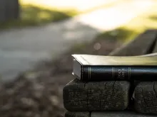 A Bible laying on a park bench.