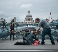A man giving a donation to a homeless person.