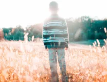A young boy standing in a field.